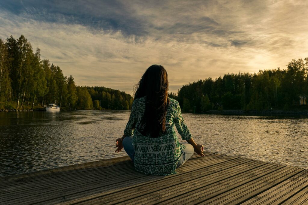 Resilienz -Eine Frau sitzt auf einem Steg vor einem See